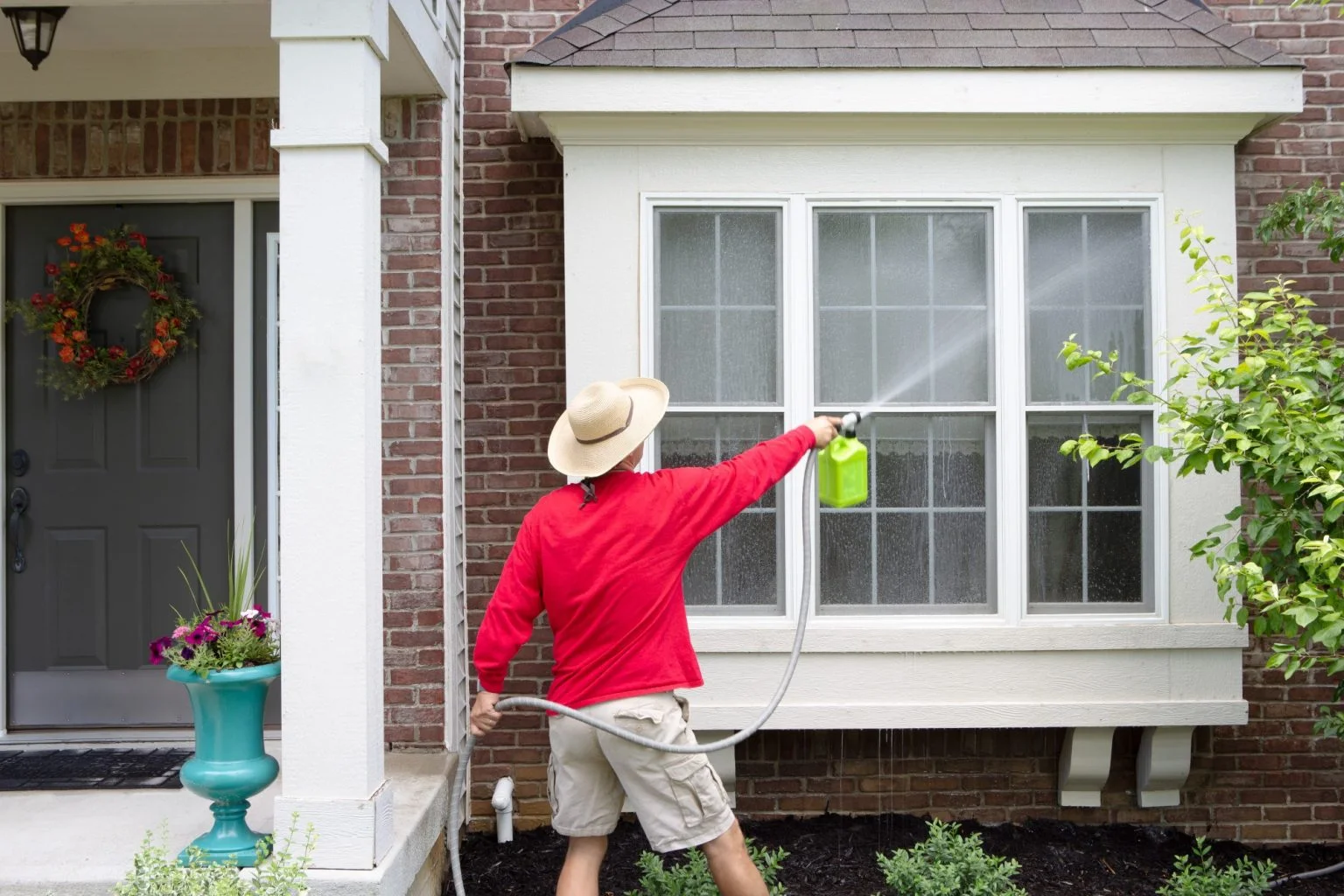 man washing exterior of home